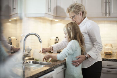 Grandmother and granddaughter washing vegetables in kitchen