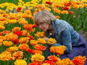 Mature woman smelling flowers at field
