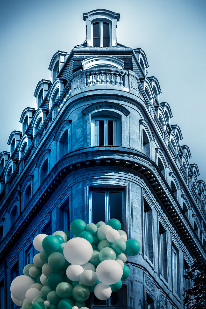 LOW ANGLE VIEW OF BALLOONS AGAINST BUILDING AGAINST SKY