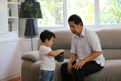 Grandfather and grandson using virtual reality simulator at home