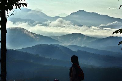 Rear view of woman looking at mountains against sky