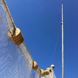 Low angle view of clothes hanging against clear blue sky