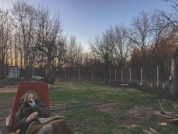 Man relaxing on field in park against sky