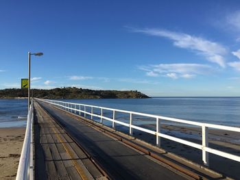 Empty pier over sea against blue sky