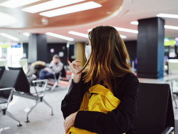 Side view of woman sitting on chair at airport