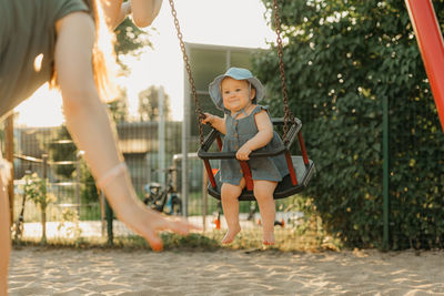 Portrait of young woman standing on swing