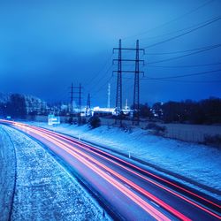 Light trails on road against sky during winter