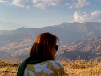 Rear view of woman looking at mountains against sky