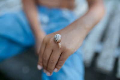 Midsection of boy with snail on hand