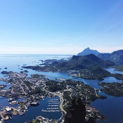 Aerial view of city by sea against clear blue sky