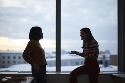 Women standing against window and talking