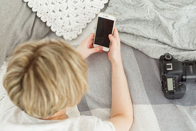 Rear view of woman using mobile phone at home