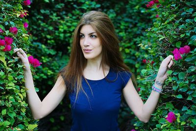 Young woman standing by pink flowers