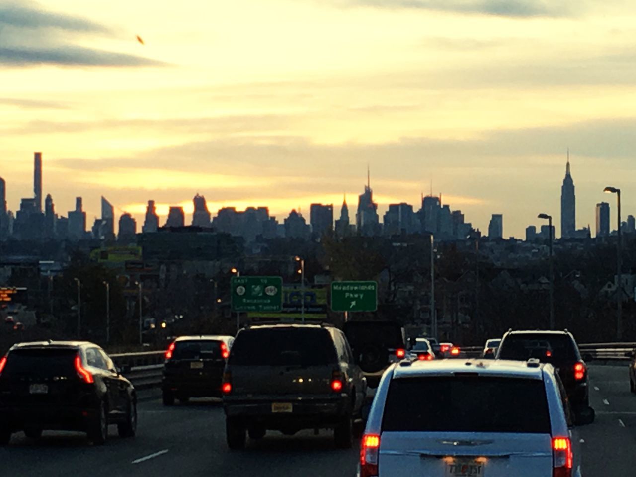 sunset, architecture, transportation, building exterior, city, car, built structure, land vehicle, mode of transport, sky, road, cityscape, orange color, travel, traffic, street, travel destinations, capital cities, cloud - sky, tower