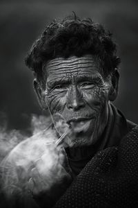 Close-up portrait of senior man smoking pipe