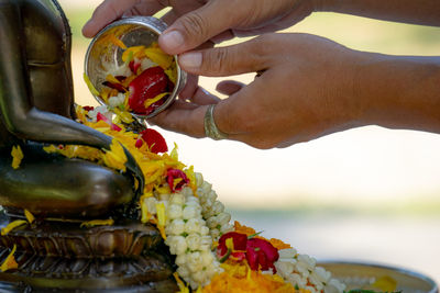 Cropped hands of person pouring water on statue