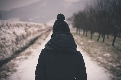 Rear view of person walking on snow covered pathway