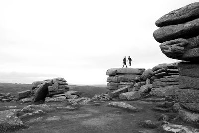 People on rock formations against sky