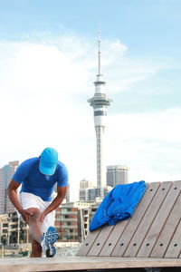 Man stretching against sky in city