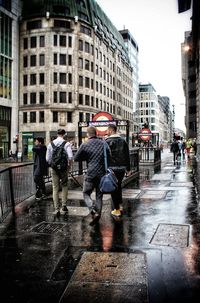 Rear view of people walking on wet street in rainy season