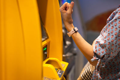 Woman using wireless system on smart watch at atm cash machine