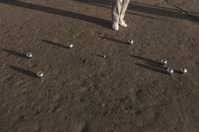 Low section of person standing by balls on mud 