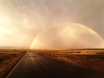 Scenic view of rainbow over landscape against sky