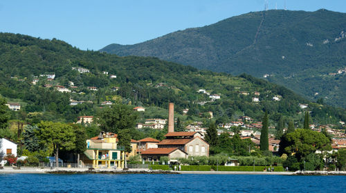 Scenic view of lake by buildings and mountains against sky