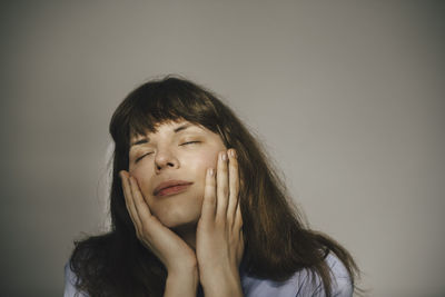 Portrait of young woman against gray background