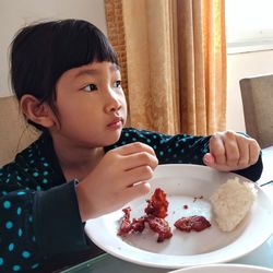Thoughtful girl having food in plate at table