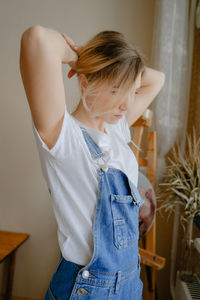 Side view of young woman standing against wall
