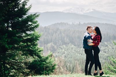 Side view of young couple standing face to face in forest