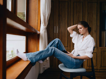 Young woman looking through window