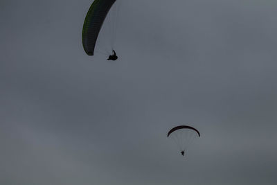 Low angle view of people flying kite against sky