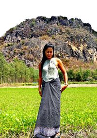 Portrait of smiling young woman standing on field