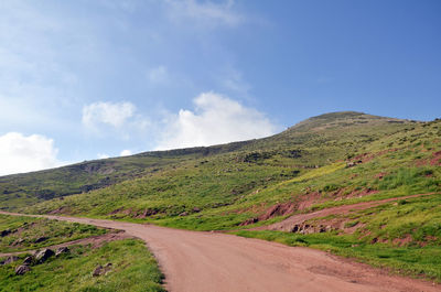 Road amidst green landscape against sky