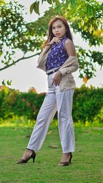 Portrait of woman standing on field against trees