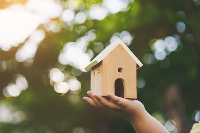 Hand holding small toy against building