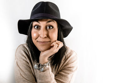Portrait of young woman wearing hat against white background