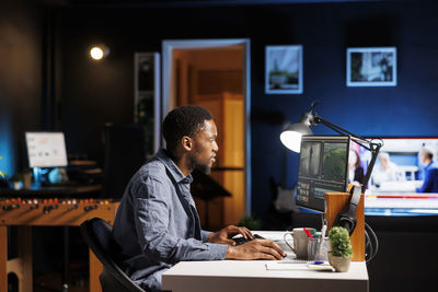 Side view of young woman using mobile phone while sitting at home