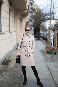 Portrait of woman standing on footpath