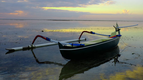 Boats in calm sea at sunset