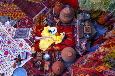 Directly above shot of woman lying on bed amidst multi colored carpets