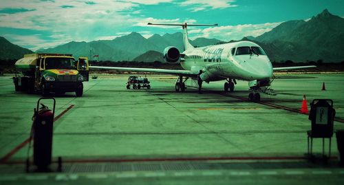 Airplane on airport runway against mountains