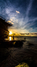 Silhouette man on beach against sky during sunset