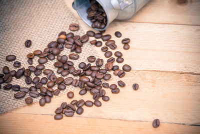 Roasted coffee beans spilling from milk canister on table