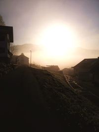 Road amidst buildings against sky during sunset