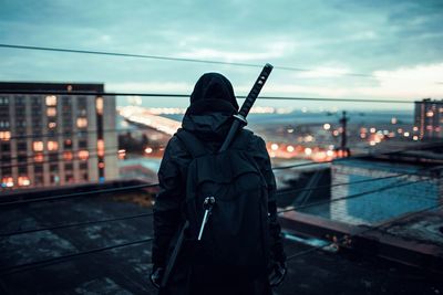 Rear view of person standing with sword on terrace in city