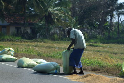 Full length of farmer with sacks by field on road