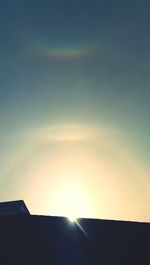 Low angle view of sun shining through clouds